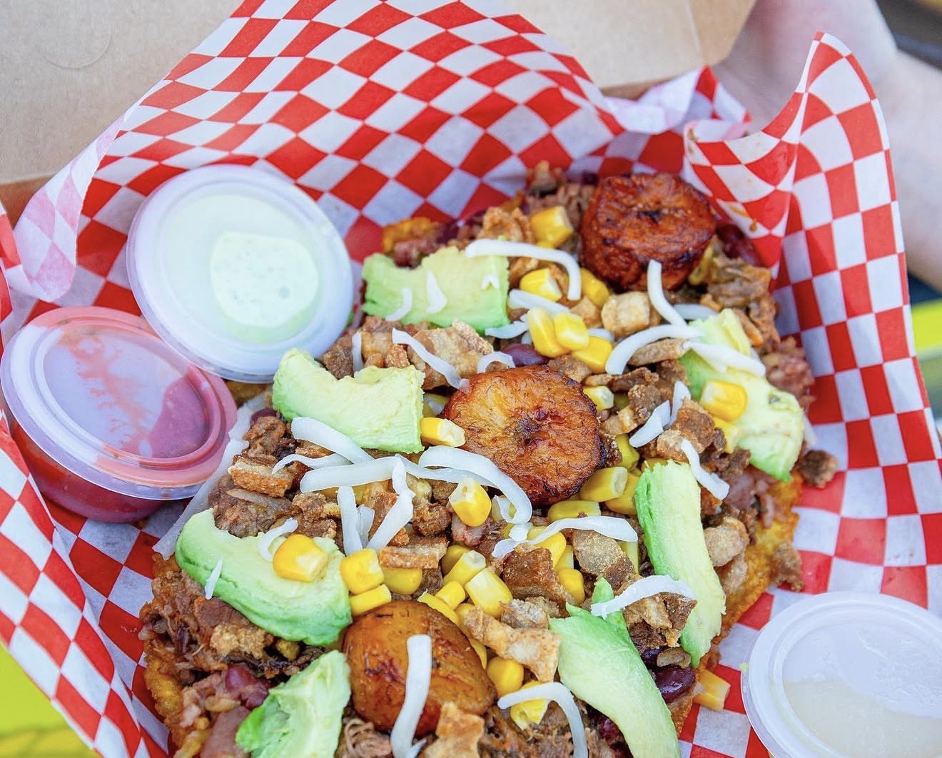 Loaded patacón topped with meat, corn, avocado and sweet plantains
